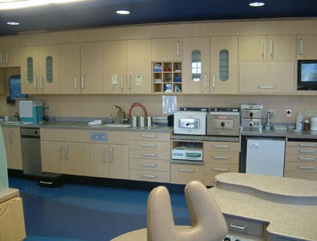 Modern orthodontic office treatment room with dental chairs, cabinets, and clinical equipment.